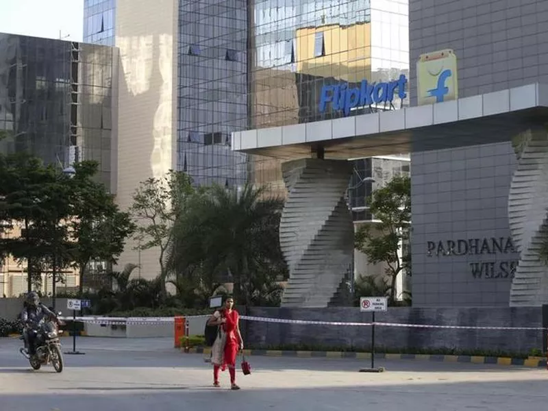 A motorist and a woman walks past a building that formerly was the Flipkart headquarters in Bangalore, India. (AP)
