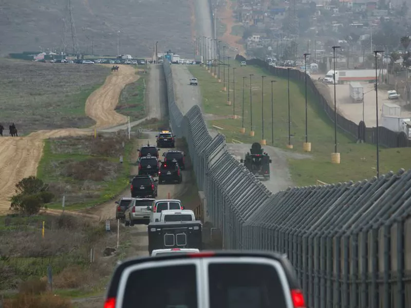 Border Patrol agent Eduardo Olmos walks near the secondary fence separating Tijuana, Mexico, background, and San Diego in San Diego. (AP).