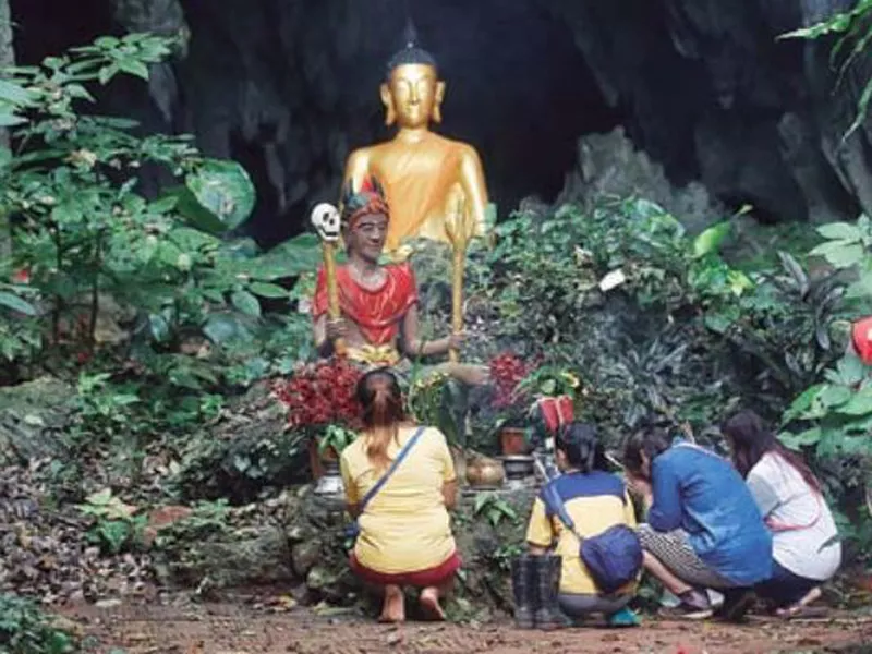Family members pray in front of a Buddhist statue near a cave where 12 boys and their soccer coach have been trapped. (AP)