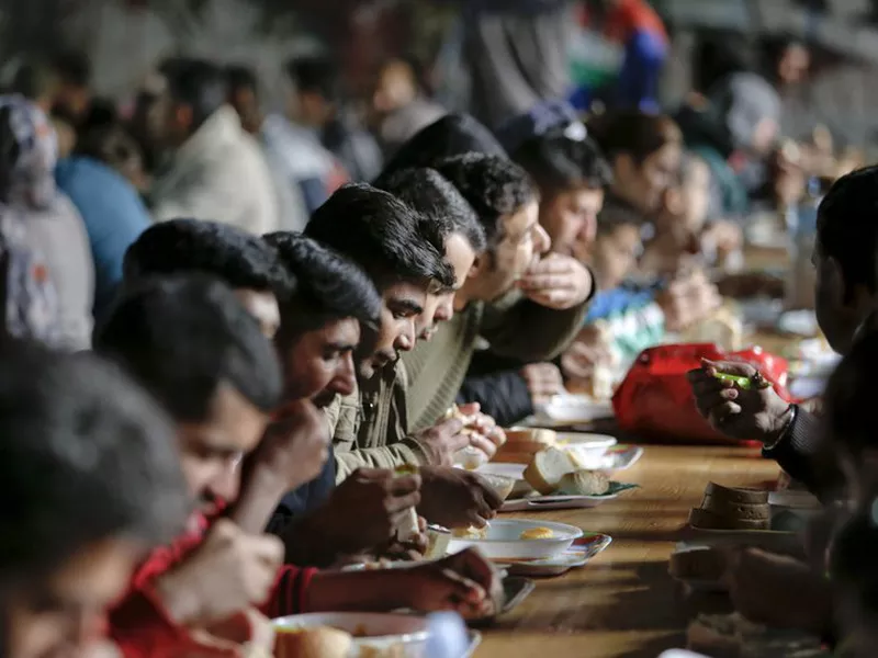 In this Saturday, May 12, 2018 picture, migrants eat lunch in the abandoned building of a former hotel. (AP)