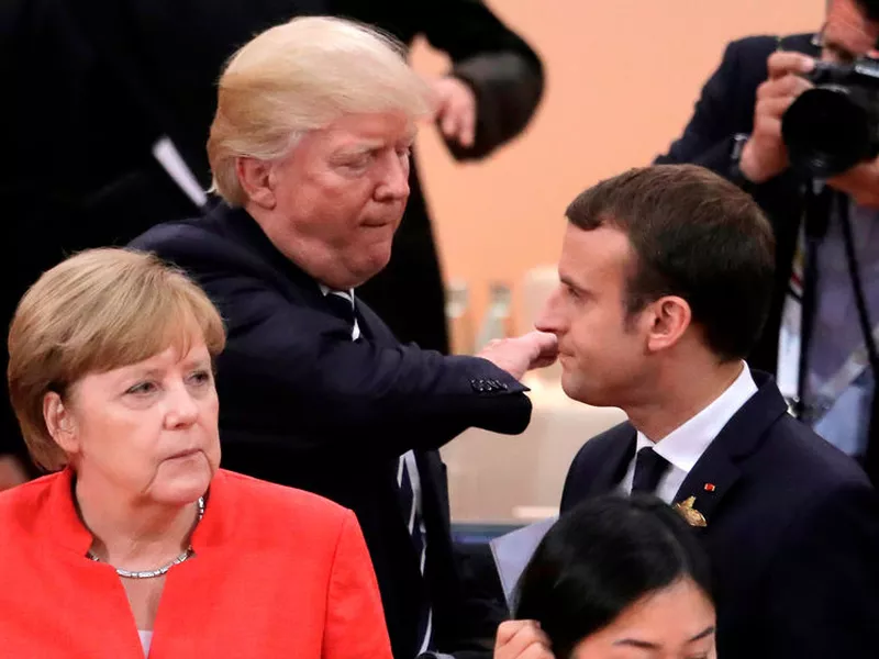 German Chancellor Angela Merkel, front, looks on as U.S. President Donald Trump, center, pads the shoulder of France’s President Emmanuel Macronm in Hamburg, northern Germany. (AP)
