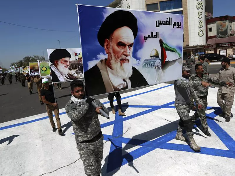 Supporters of Iraqi Hezbollah brigades march on a representation of an Israeli flag with a portrait of late Iranian leader Ayatollah Khomeini and Iran’s supreme leader Ayatollah Ali Khamenei, in Baghdad, Iraq. (AP)