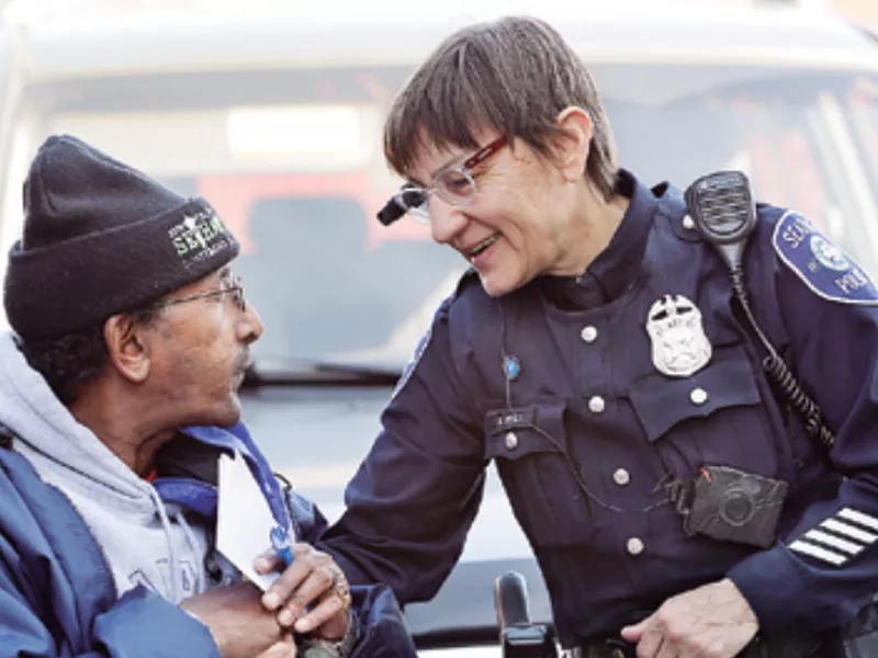 Seattle police officer Debra Pelich, right, wears a video camera on her eyeglasses as she talks with Alex Legesse before a small community gathering in Seattle. (AP)
