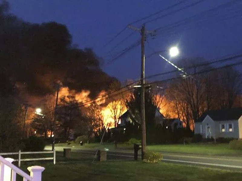 This photo provided by WFSB-TV shows a fire behind a house, in North Haven, Conn. A Connecticut woman’s call to police to report domestic.