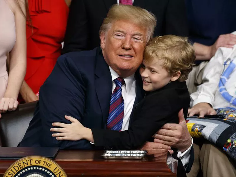 President Donald Trump hugs Duchenne Muscular Dystrophy patient Jordan McLinn after signing the “Right to Try” act in the South Court Auditorium on the White House campus, in Washington.