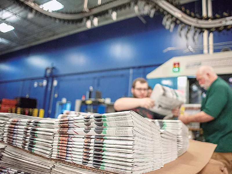 Production workers stack newspapers onto a cart at the Janesville Gazette Printing & Distribution plant in Janesville, Wis.