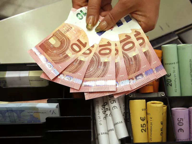 Euro coins and banknotes are shown by a salesclerk at a shop in Vilnius, Lithuania. Italy’s economy minister says the new populist government isn’t discussing any proposal to leave the eurozone.