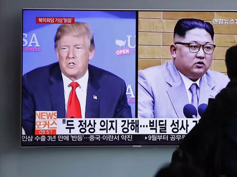 A man watches a TV screen showing file footage of U.S. President Donald Trump, left, and North Korean leader Kim Jong Un. (AP)