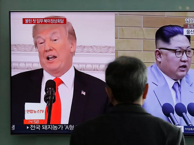 A man watches a TV screen showing file footages of U.S. President Donald Trump, left, and North Korean leader Kim Jong Un, right.