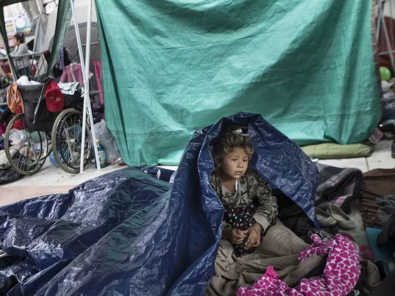 A girl who traveled with the annual caravan of Central American migrants awakens where the group set up camp to wait for access to request asylum in the U.S., outside the El Chaparral port of entry building at the US-Mexico border in Tijuana, Mexico. (AP)