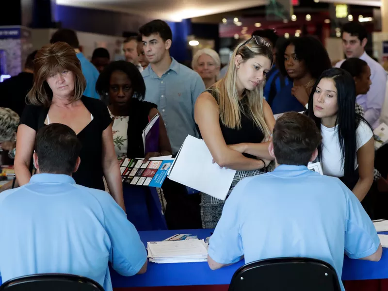 Job applicants talks with representatives from Aldi at a job fair hosted by Job News South Florida, in Sunrise, Fla.