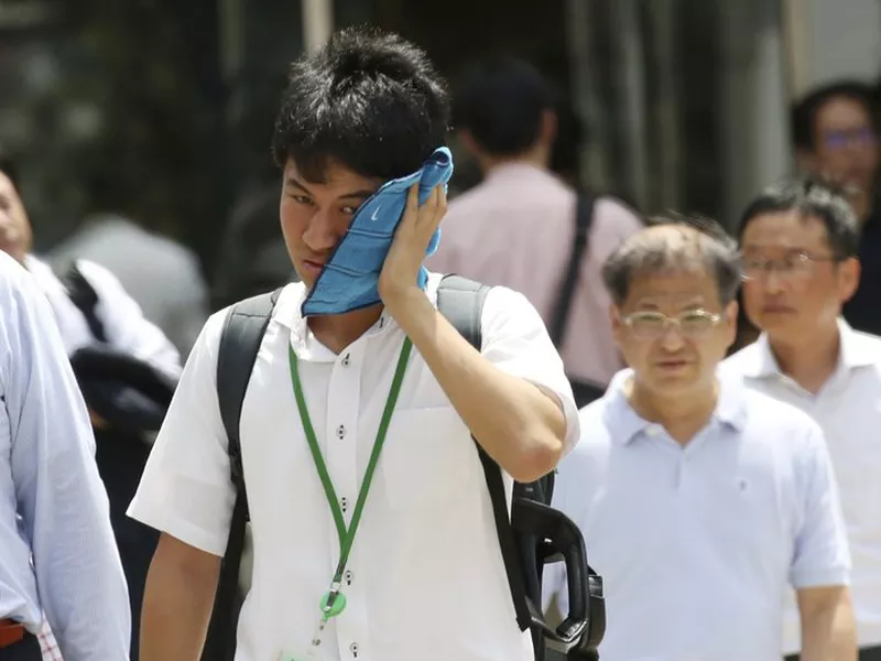 A man wipes the sweat from his face in the scorching heat at a business district in Tokyo. (AP)