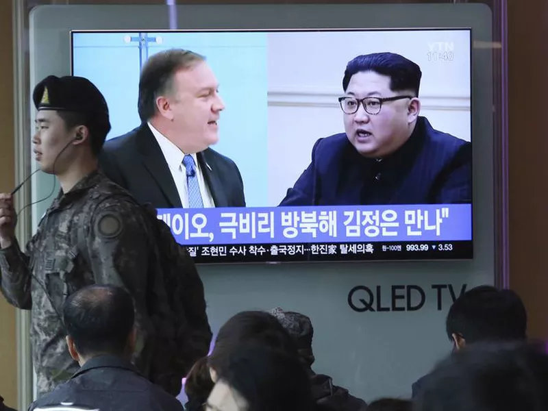 A South Korean army soldier passes by a TV screen showing file footage of CIA Director Mike Pompeo, left, and North Korean leader Kim Jong Un during a news program at the Seoul Railway Station in Seoul, South Korea.