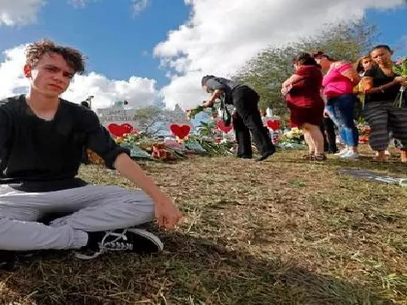 Chris Grady, a student at Marjory Stoneman Douglas High School, sits at a memorial in Parkland, Fla. for those slain in the Feb. 14 school shooting.