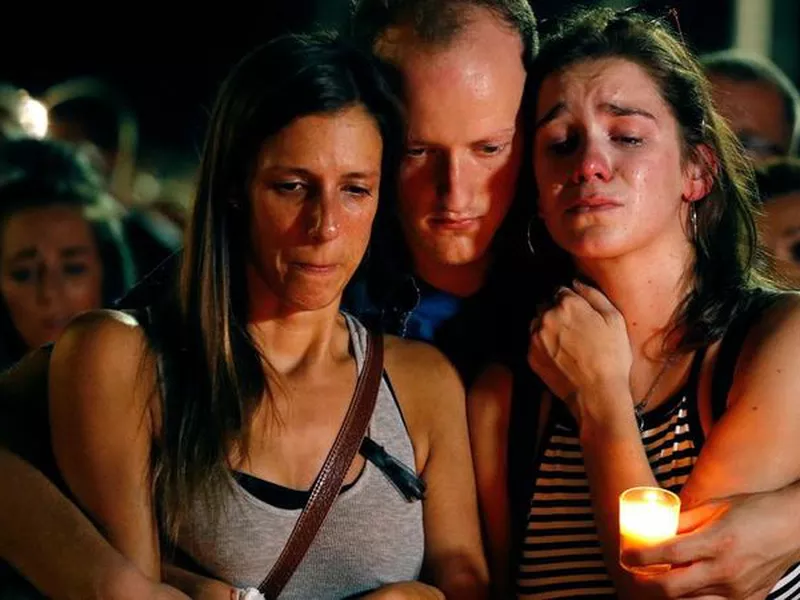Mallory Cunningham, left, Santino Tomasetti, center, and Aubrey Reece attend a candlelight vigil.