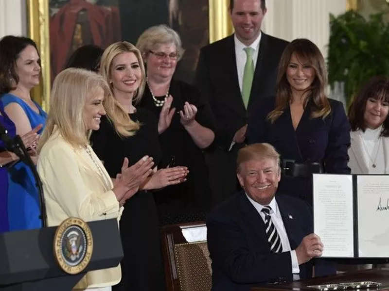 President Donald Trump holds up an executive order he signed.