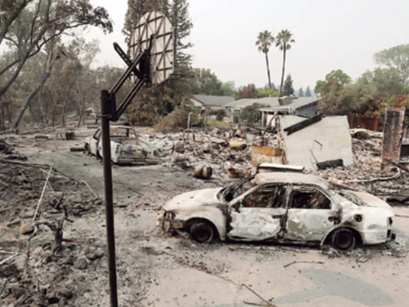 Burned vehicles sit in front of a wildfire-ravaged home, in Redding, Calif.