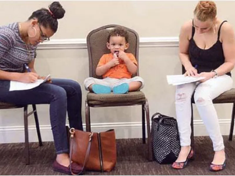 Joan Herrera, center, sits and waits as his mother Andrea Batista Garcia, left, and Marlene Gonzales, fill out job applications while attending the Great Northeast 2018 Job Fair at Capriotti’s in McAdoo, near Hazleton, Pa.