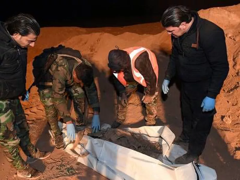 Syrian security forcé members check human remains  at the site of two graves, near the northern city of Raqqa, Syria.