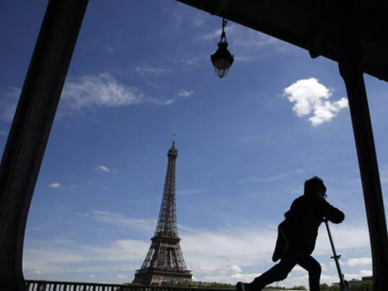 A boy rides his scooter on the Bir Hakeim bridge as the Eiffel Tower is seen background in Paris.