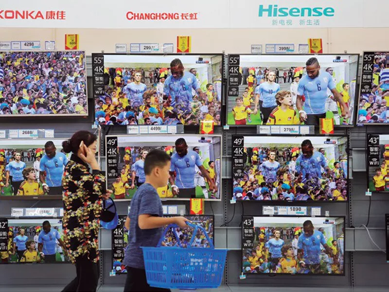 Woman and a child pass Chinese brands of flat screen TVs on display at a hypermarket in Beijing.