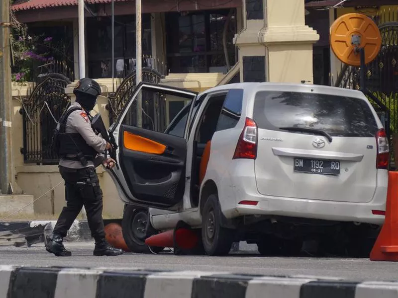 Officers move into position following an attack at the regional police headquarters in Pekanbaru, Riau province, Indonesia.