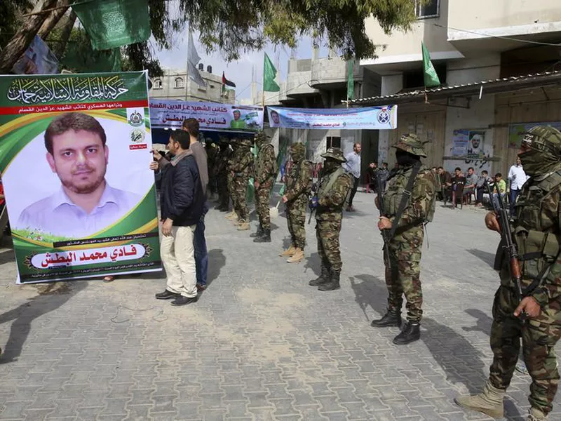 Relatives hold a sign next to the soldiers of the Izzedine al-Qassam Brigades, a military wing of Hamas.