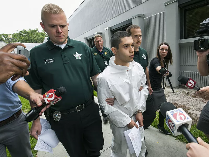 Marion County Sheriff’s Detectives John Lightle, left, and Dan Pinder, right, escort a handcuffed and shackled Sky Bouche, 19, center, to a waiting patrol car, in Ocala, Fla. Bouche is the suspect in a shooting.