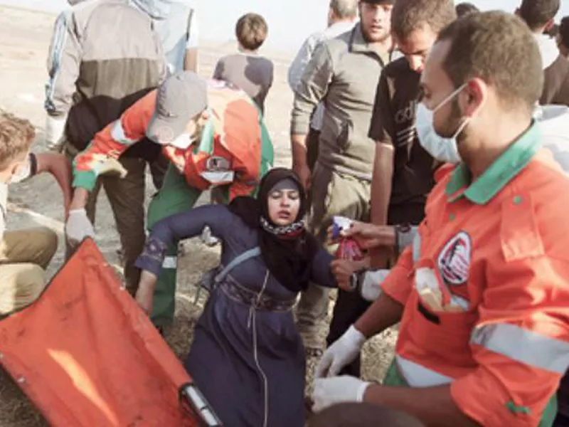 Palestinian medics help a woman who fainted from teargas fired by Israeli troops during a protest at the Gaza Strip’s border with Israel. (AP)