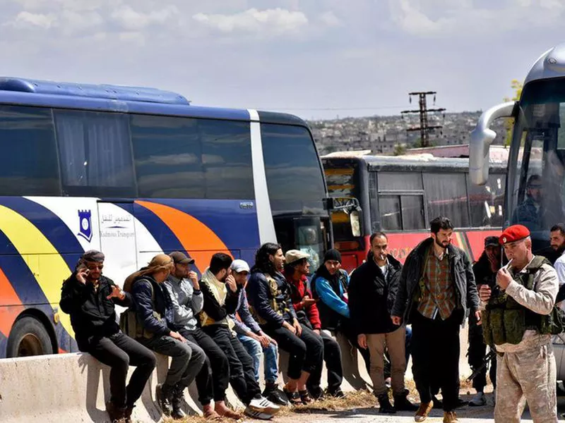 Syrian government forces oversee the evacuation by buses of opposition fighters and civilians.